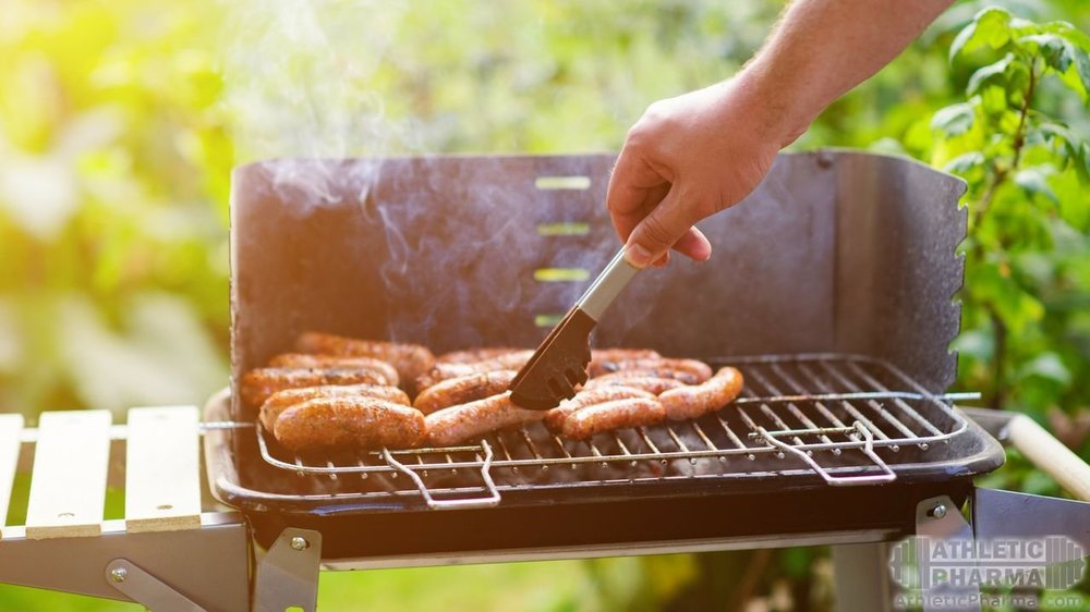 Жарит сосиски на барбекю