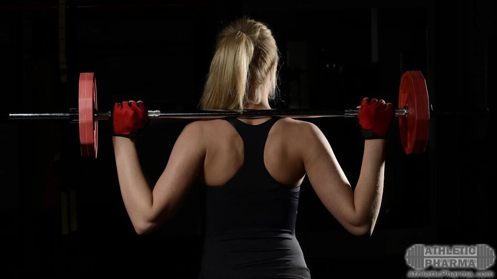 Девушка тренируется со штангой