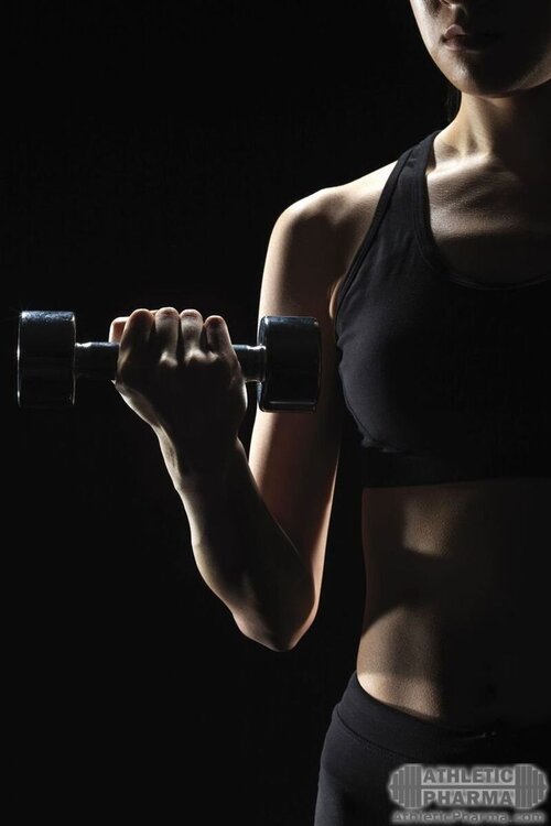 Девушка тренируется с гантелью